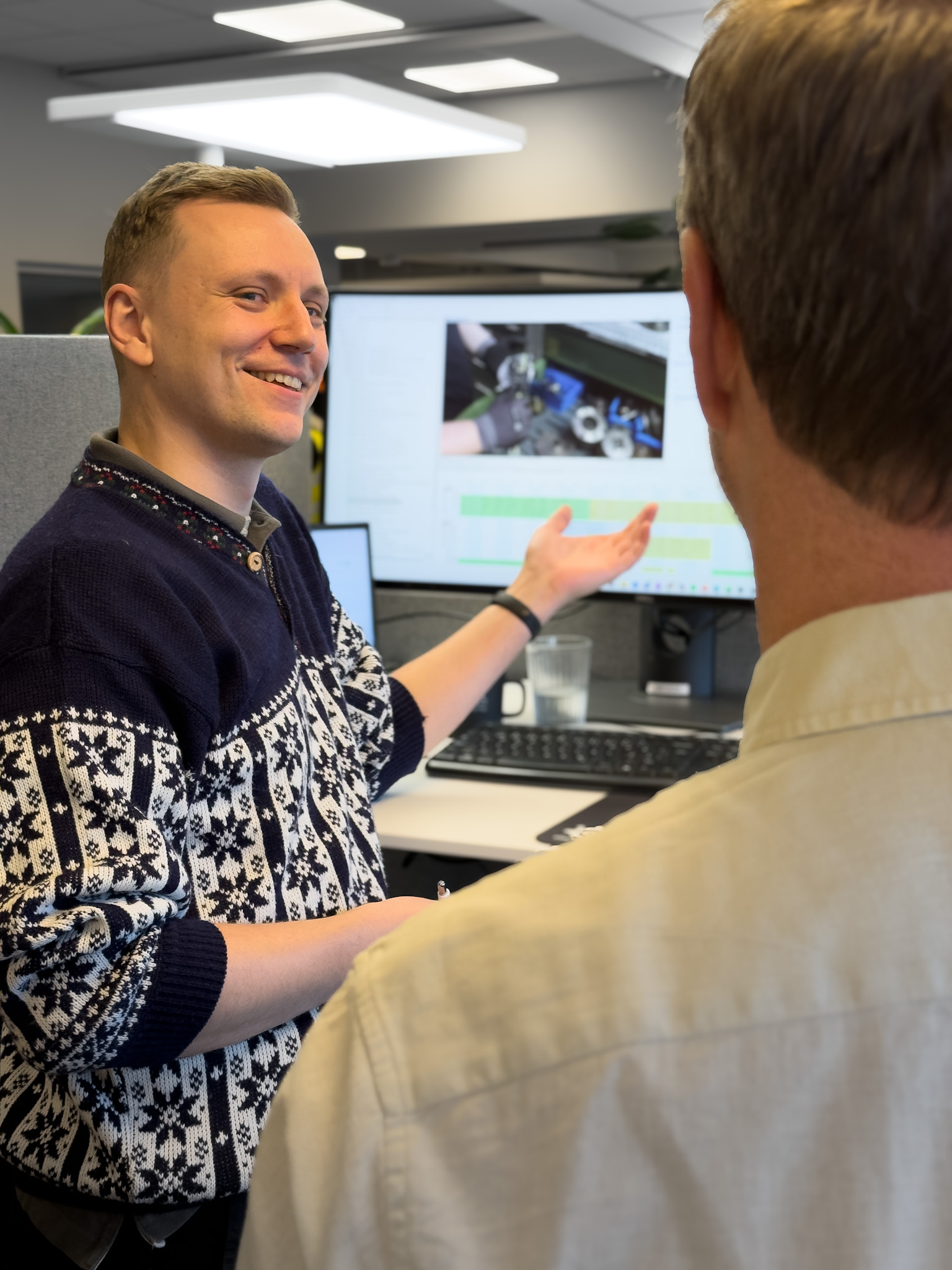 Two colleagues discuss a time study in front of a screen to achieve efficient production with digital tools and new technology.